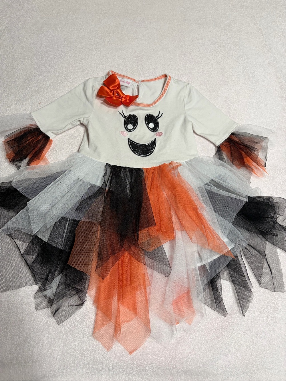 Cutie Halloween costume Has orange, black, and white tulle skirt and wrists.